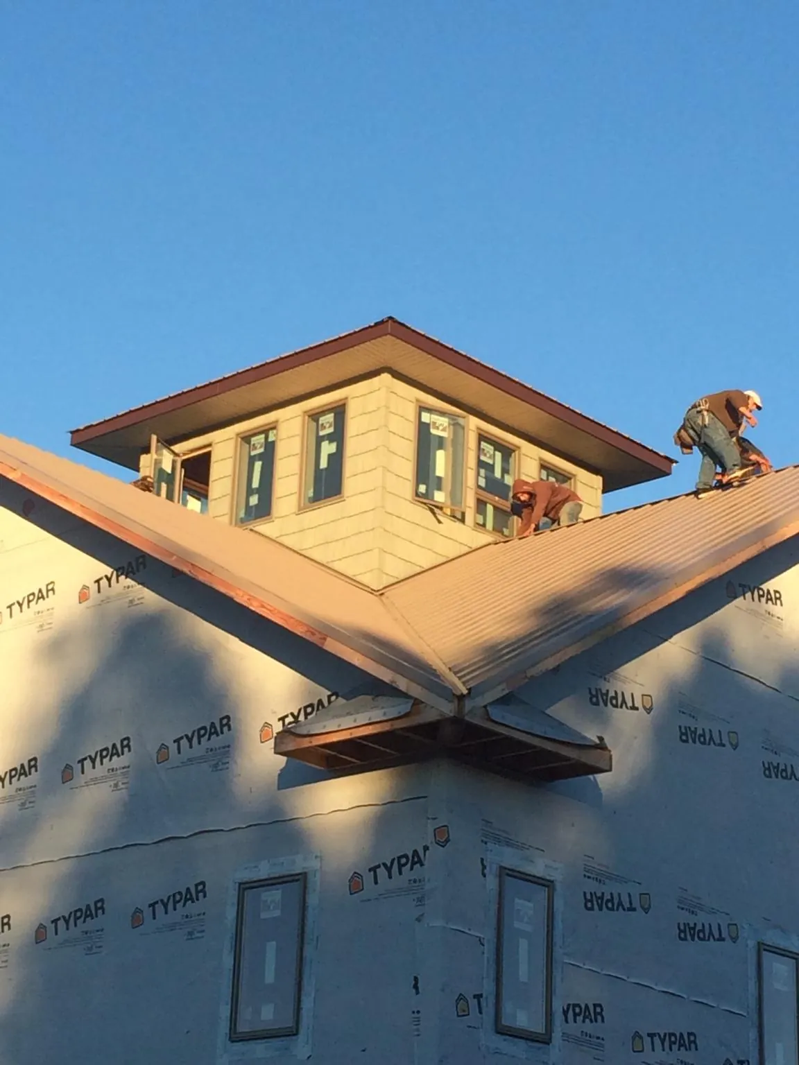 Roofers working around a rooftop cupola on a new metal roof at sunset — Roof Waterproofing in Amboy by Roofing Brothers